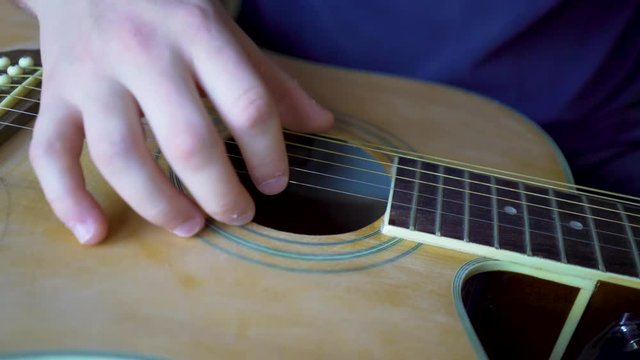 Very closeup on finger plucking the strings on the slide guitar.