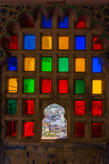 Town view from the colorful mosaic window in City Palace museum of Udaipur, Rajasthan, India
