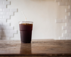 Iced black coffee on wooden table and wall white color