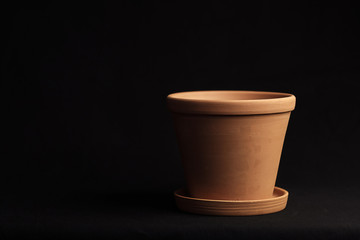 clay pot empty on a black background, part of the pot goes into the dark