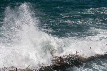 Wave crashing over coastal swimming hole