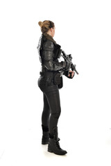 full length portrait of female  soldier wearing black  tactical armour, holding a rifle gun, isolated on white studio background.