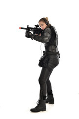 Naklejka premium full length portrait of female soldier wearing black tactical armour, holding a rifle gun, isolated on white studio background.