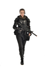 full length portrait of female  soldier wearing black  tactical armour, holding a rifle gun, isolated on white studio background. © faestock
