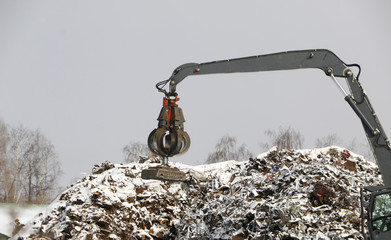 The hydraulic grab cleans and tampens the metal debris. The excavator lifts and throws the load...