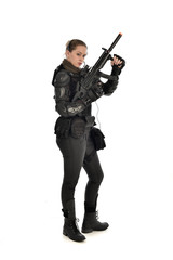 Fototapeta premium full length portrait of female soldier wearing black tactical armour, holding a rifle gun, isolated on white studio background.