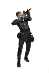 full length portrait of female  soldier wearing black  tactical armour, holding a rifle gun, isolated on white studio background.