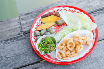 The delicious pork scratching or pork crackling snack food tradition Thai cuisine menu with herbs, yam or sweet potato boiled, cabbage, chili youth local popular meal in Chiang mai province Thailand.
