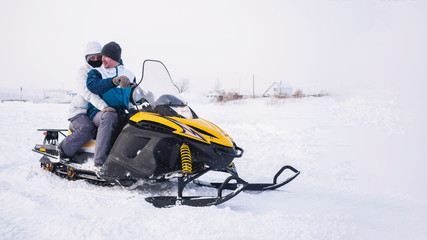 Couple of man and woman in the snowmobile. Winter snow field