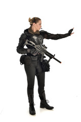 full length portrait of female  soldier wearing black  tactical armour, holding a rifle gun, isolated on white studio background.