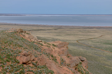 red sandstone outcrops of Big Bogdo sacred mountain and Baskunchak salt lake in vast grasslands on...