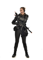 full length portrait of female  soldier wearing black  tactical armour, holding a rifle gun, isolated on white studio background.