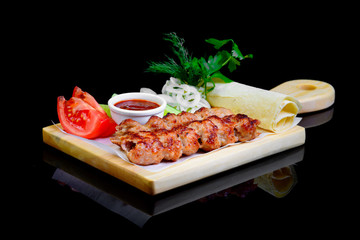 Fried grilled meats with vegetables on a black background