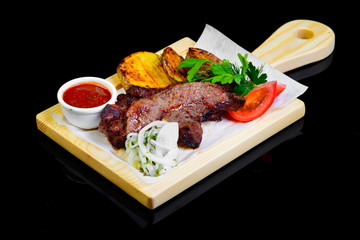 Fried grilled meats with vegetables on a black background