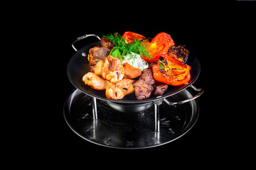 Fried grilled meats with vegetables on a black background