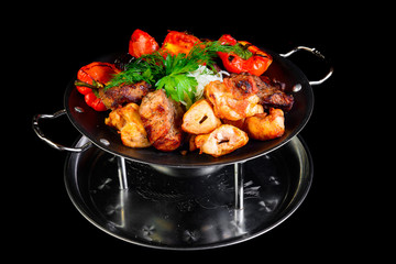 Fried grilled meats with vegetables on a black background