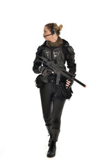 Fototapeta premium full length portrait of female soldier wearing black tactical armour, holding a rifle gun, isolated on white studio background.