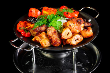 Fried grilled meats with vegetables on a black background
