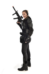 full length portrait of female  soldier wearing black  tactical armour, holding a rifle gun, isolated on white studio background.