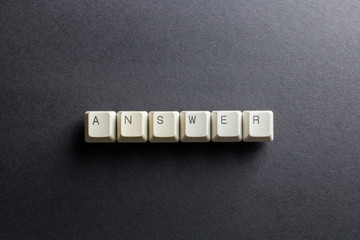 Word answer made using computer keyboard buttons on a black background. IT technology concept.