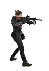 full length portrait of female  soldier wearing black  tactical armour, holding a rifle gun, isolated on white studio background.