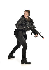 full length portrait of female  soldier wearing black  tactical armour, holding a rifle gun, isolated on white studio background.