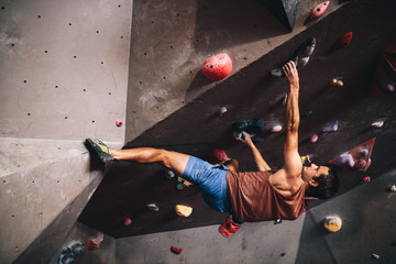Man climbing indoor boulder wall - obrazy, fototapety, plakaty