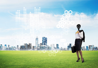 Camera headed woman standing on green grass against modern cityscape