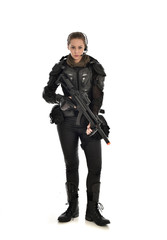 full length portrait of female  soldier wearing black  tactical armour, holding a rifle gun, isolated on white studio background.