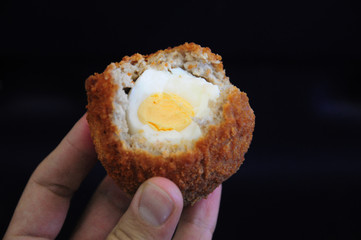 Traditional british food. Half eaten Scotch egg. Hard boiled-egg wrapped in sausage meat coated in...