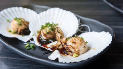 Fresh japanese scallop with black sauce in plate