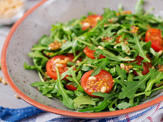 Dietary menu. Vegan cuisine. Healthy salad with arugula, tomatoes and pine nuts.