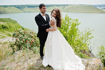 Wedding couple at breathtaking landscape with rock and lake.
