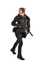 full length portrait of female  soldier wearing black  tactical armour, holding a rifle gun, isolated on white studio background.