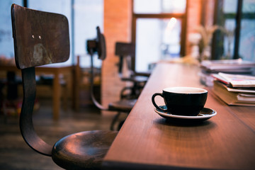 Hot coffee cup on wooden table in vintage cafe with book background , interior