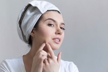 Young woman with acne in bathroom. Portrait of teenager girl looking at the mirror on her skin. Beauty, skin care lifestyle concept.