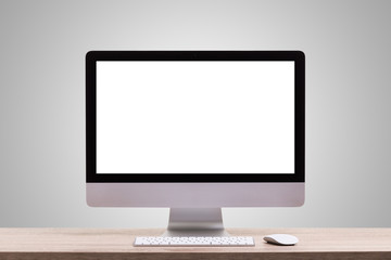 Modern desktop computer on wooden table. Studio shot isolated on blank grey. Blank screen for graphics display montage