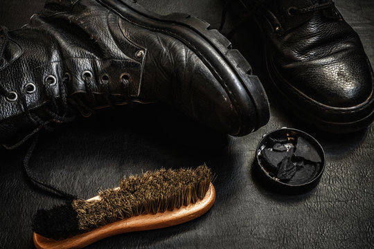 Men's military boots rme shoes, brush and shoe polish against a dark background flat lay top view