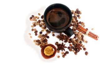 Naklejka premium Coffee in a black ceramic cup, coffee beans, star anise, cinnamon sticks, candy. Isolate on white.