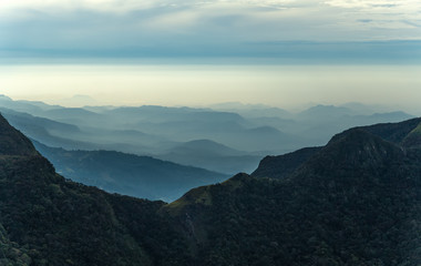 Fototapeta premium Sunrise in meadows and mountains landscape, Worlds End in Horton Plains National Park Sri Lanka.