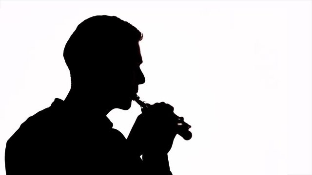 The guy plays the flute in the style of beatbox. Profile of the musician. Copy space. Silhouette. Isolated.