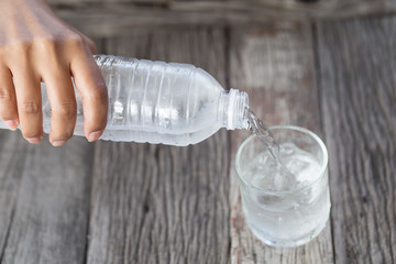 close up of Woman's Hand Pouring Fresh Pure drinking water in glass,health,wellbeing,healthcare, diet as lifestyle hydration concept on wooden table background