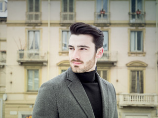 Handsome bearded young man outdoor in winter fashion, wearing black turtleneck sweater and woolen blazer jacket in city setting