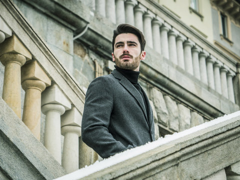 Handsome bearded young man outdoor in winter fashion, wearing black turtleneck sweater and woolen blazer jacket in city setting