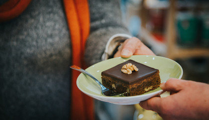 One hand reaches out to another hand with a plate of walnut cake