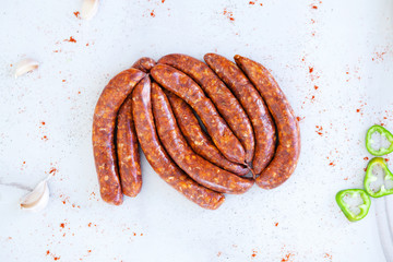 Bundle of raw sausages on a white background with a paprika, top view
