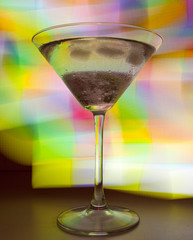 A martini glass with a cocktail in beautiful light of different colors