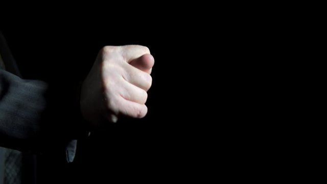 Hand of a businessman shows a figs gesture on a black background, close up shoot.