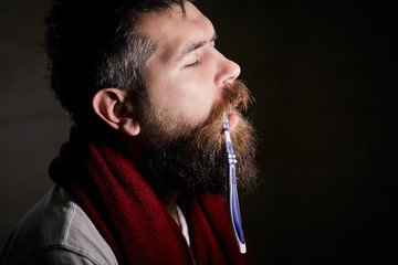 sleepy bearded man brushing teeth with a toothbrush in front of the bathroom mirror in morning. man...