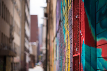 Naklejka premium Abstrakcyjny widok śródmieścia allyway w Johannesburgu, jasno ozdobiony kolorowymi graffiti, skupiony na pierwszym planie i zamazany w oddali
